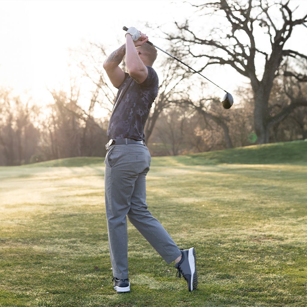 Golfer wearing a Stay Grassy polo raking a bunker