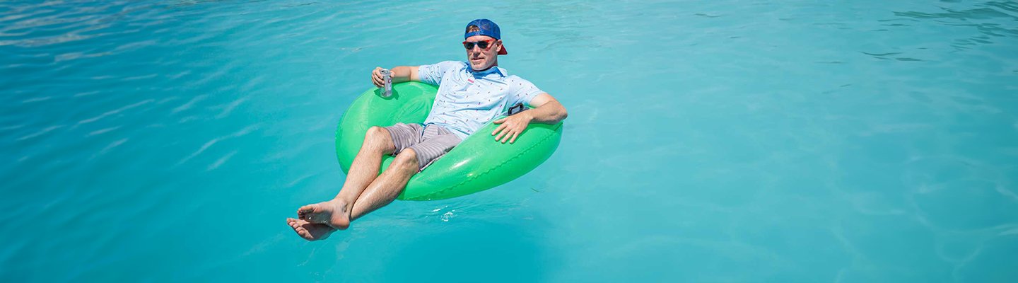 Guy on a raft in a swimming pool wearing a F. King Golf Pool Party polo